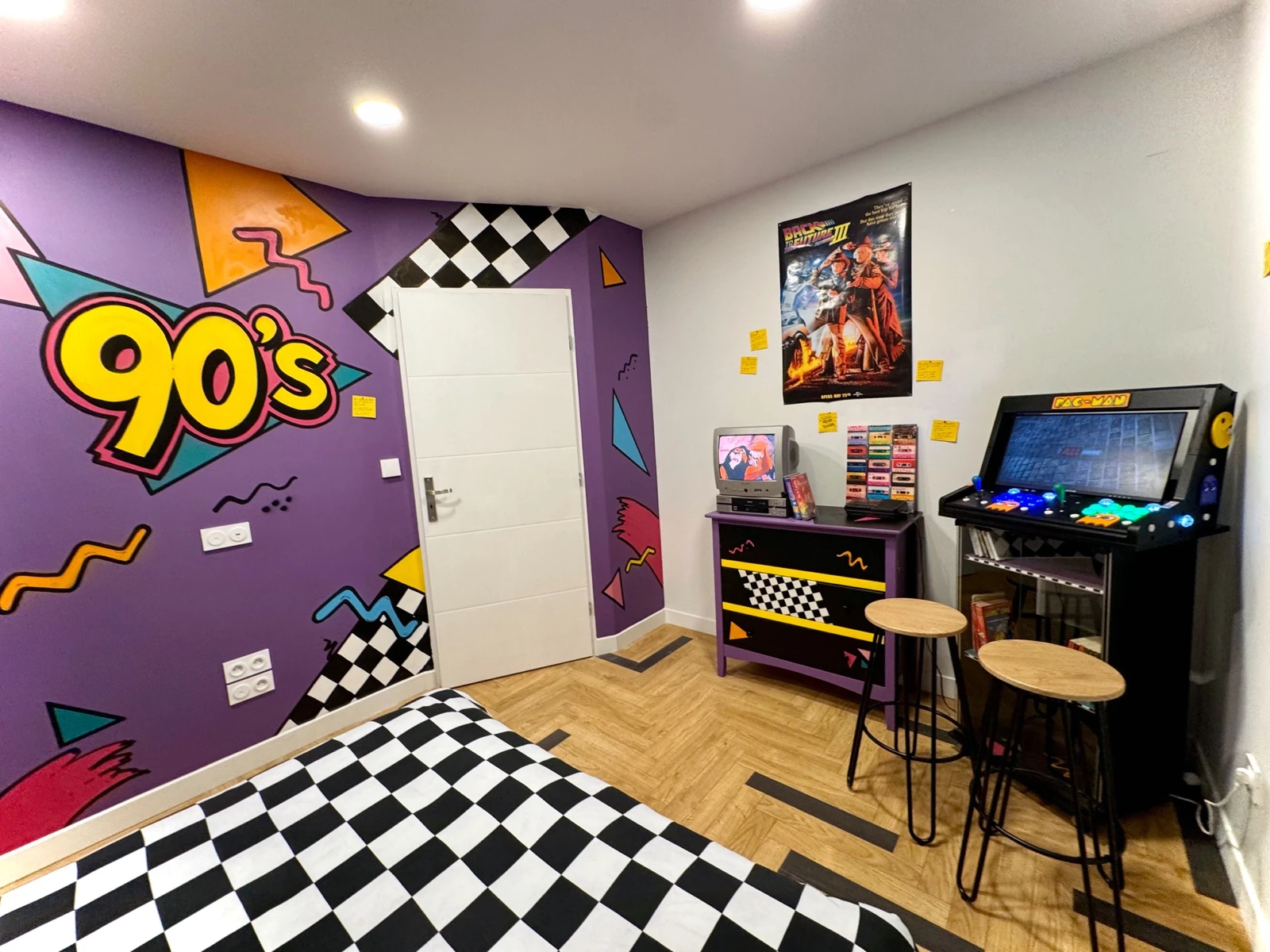 Chambre années 90 du logement, damier, fresque violette et borne d’arcade.